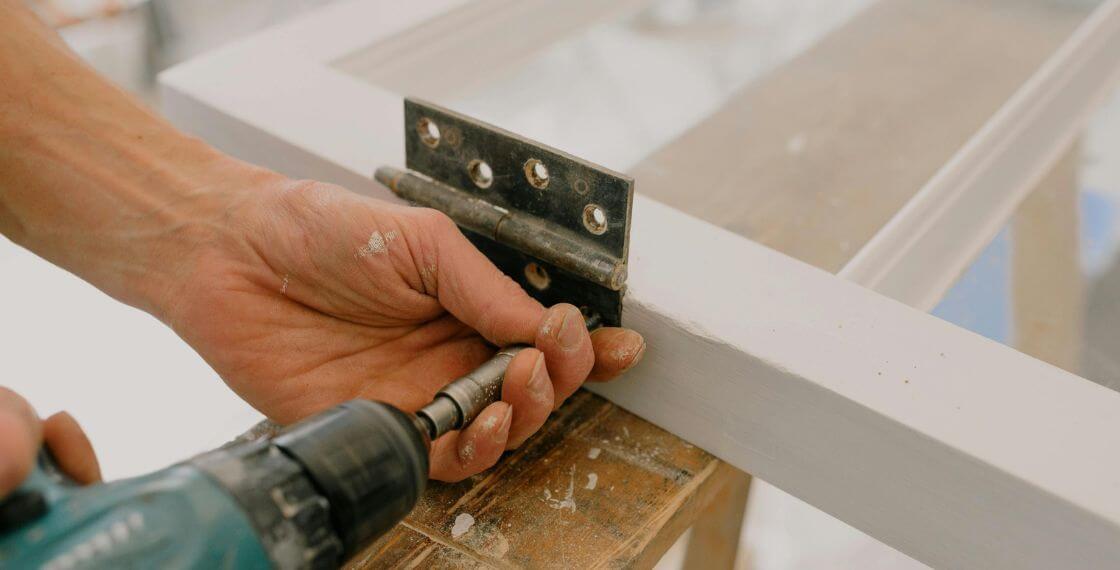 Como Reparar Portas em Casa - trabalhador colocando dobradiça na porta